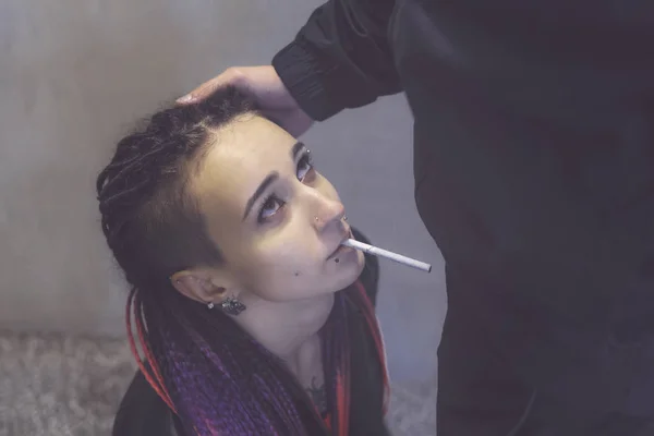 Una chica triste con un cigarrillo en la boca mira al joven sosteniendo su cabeza. Publicidad antitabaco. La nicotina causa un debilitamiento de la potencia masculina. Adicción al tabaco — Foto de Stock
