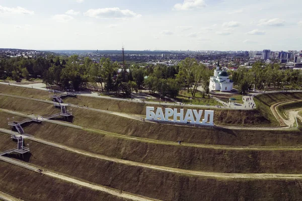 A picturesque bird\'s eye view to letters on the slope spelling out a Russian city\'s name BARNAUL. panoramic view to stepped-made hill with big letters forming city name. Capital letters on the hill.