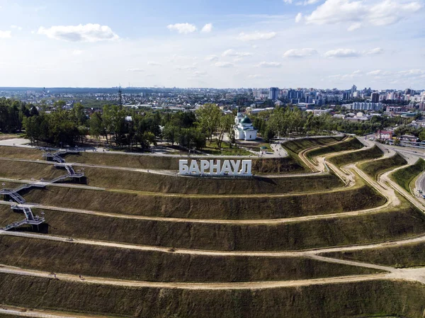 Well-planned walking area on the hill with the letters spelling out a Russian city\'s name on the top. A view from a height to developed landscape of upland with the brand of the city on the top.