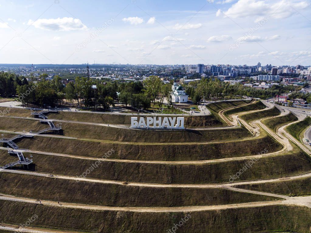 Well-planned walking area on the hill with the letters spelling out a Russian city's name on the top. A view from a height to developed landscape of upland with the brand of the city on the top.