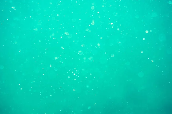 Underwater turquoise texture in ocean. Bubbles in tropical sea.