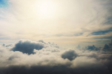 Bir kuşun uçuşunda çekilen bulutların altında, Güneş bulutların üzerinde parlar.