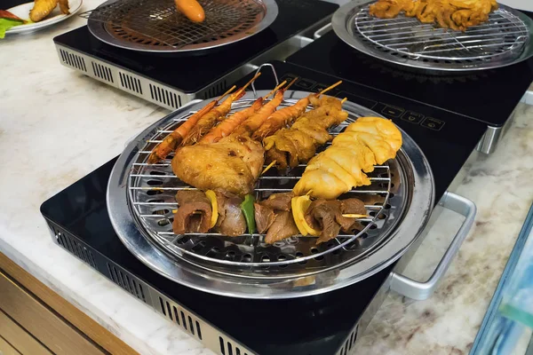 Different types of kebabs are fried on a safe electric grill in the kitchen of the restaurant. Cooking at home. Fried shrimp, chicken, beef, pork fried on the grill.