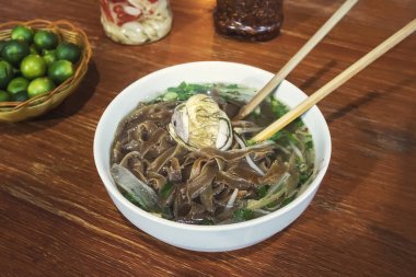 Bir kapta fermente balut yumurtası. Restoranda masada Pho noodle ile egzotik bir çorba. Sokak yemekleri Vietnam geleneksel mutfağı