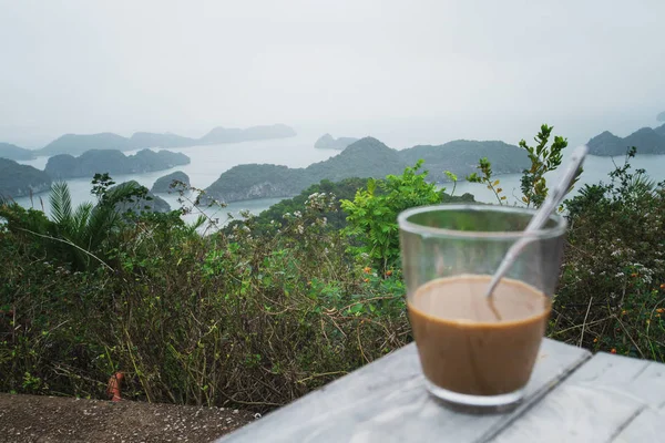 Hot milk coffee in Vietnam style. Breakfast with a beautiful view against the rocks sticking out of the water into the sea. Halong Bay in Northern Vietnam, copy space — Stock Photo, Image