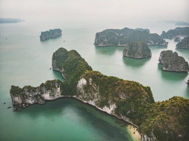 Yüksekten Halong Körfezi 'nin güzel manzarası. Suyundan sarkan kayaların üst görüntüsü. Kuzey Vietnam 'da. Deniz Burnu. Sis içindeki dağlar