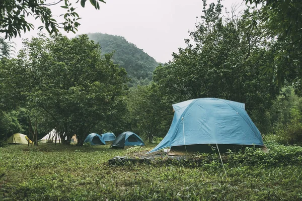 Hellblaues Kuppelzelt und Gebirgslandschaften im Hintergrund. Ferienlager mit vielen Zelten im Wald — Stockfoto