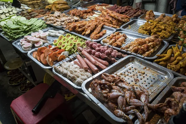 Азиатская кухня в Ханое во Вьетнаме. Уличный рынок с вьетнамской кухней. Сырая курица, сердце и ноги в подносах. сырье для гриля — стоковое фото