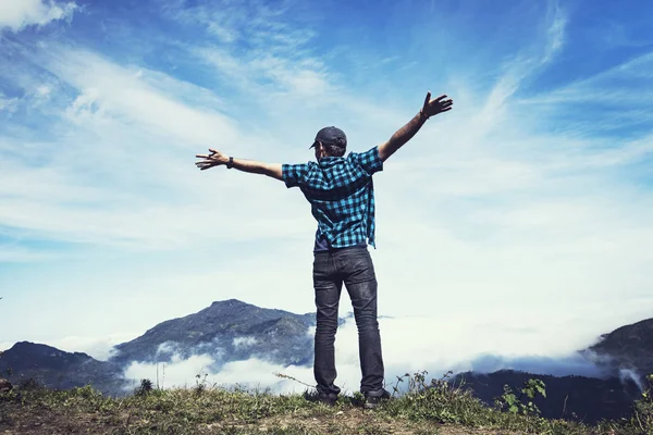 De mens spreidde zijn armen uit naar de zijkanten tegen de bewolkte blauwe lucht en hoge bergtoppen. Emotionele scène. Freedom Travel Adventure en Business Victory concept. Sterke wind in de bergen. hands-up — Stockfoto