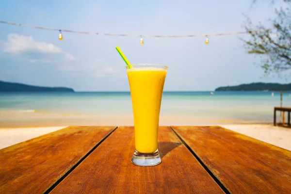 Koktéllal az asztalra, a tenger hátterét. Nyaralás, nyaralás, nyár, öröm koncepció. Finom gyümölcs rázza a háttérben egy elhagyatott strand egy trópusi szigeten Ázsiában. — Stock Fotó