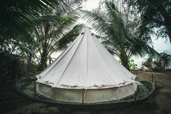 Tienda de campaña entre palmeras en una isla tropical. tienda en forma de una Yurta. wigwam moderno blanco hecho de tela para pasar la noche en la naturaleza . — Foto de Stock