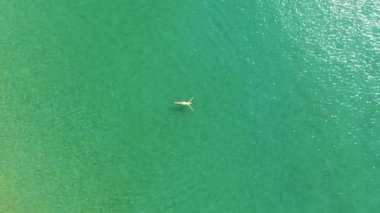 Parlak bikinili genç kadının en iyi görünümü şeffaf, mavi denizde yüzüyor. Andaman denizinin suyunda yüzen ince kadının havadan görünümü.