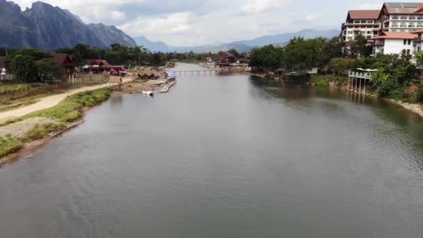 방비엥(Vang Vieng) 마을을 가로지르는 강에서 카약을 타고 있는 두 관광객의 멋진 공중 전경. 방비엥은 라오스 비엔티안 북쪽에 위치하고 있습니다. — 비디오