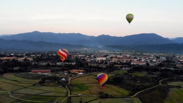 Csíkos hőlégballon repül át föld, esti táj és a város a kis házak, a folyó Laosz Vang Vieng. Laosz. — Stock videók