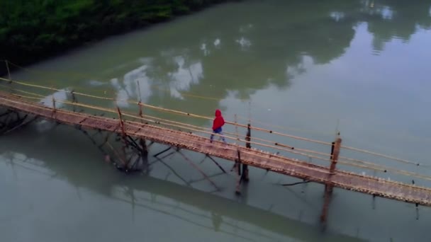 Jong meisje toeristische wandelingen op de brug van bamboe over de rivier in Luang Prabang. Met Laos. 4k zet drone — Stockvideo