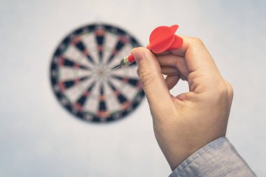 İş eğitiminin başarısı ve hedef kavramı. Yakın bir el dart tahtası merkezine doğru yeşil dart ok hedefliyor. hedefi vur. İş hayatında başarı.