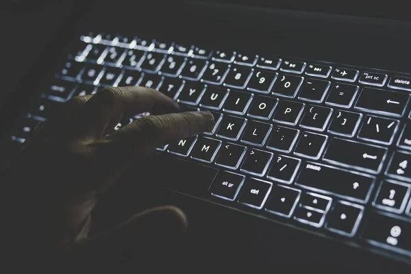 Programmeur ou pirate informatique tapant le code sur le clavier de l'ordinateur portable. clavier est allumé en lumière blanche. main appuie sur une touche sur votre ordinateur — Photo