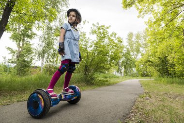 küçük kız elektrikli kendini dengeleyen bir scooter sürüyor. çocuk bir jiroscooter üzerinde dengeleme olduğunu. Kişisel eko ulaşım, gyro scooter, akıllı denge tekerleği. Popüler elektrikli ulaşım