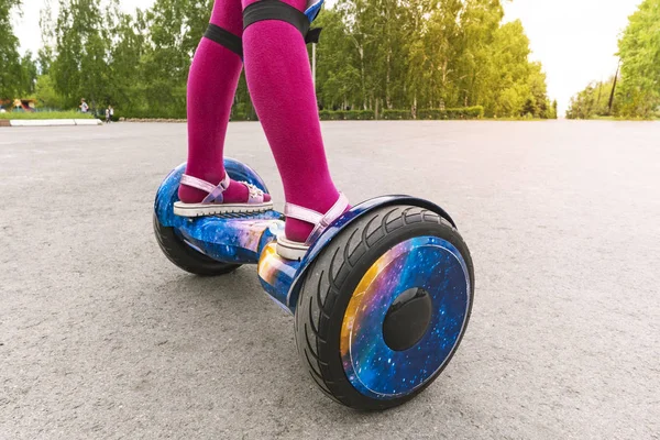 Mädchen fährt auf Gyroscooter. Füße eines kleinen Mädchens in rosa Strumpfhosen und Sandalen auf einem Gyroscooter — Stockfoto