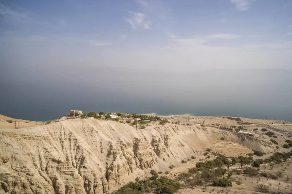 Scenic aerial view of the mountain plateau with human settlements near the Dead Sea coastline, Israel. Picturesque view of sea coast with misty horizon line. Sky meets sea and land. Skyscape