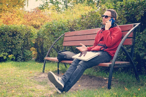 Conversation professionnelle difficile au téléphone, résolution de problèmes au travail. homme insatisfait travaillant sur ordinateur portable. Parler sur smartphone, assis dans le parc. mécontentement, mécontentement, mécontentement — Photo