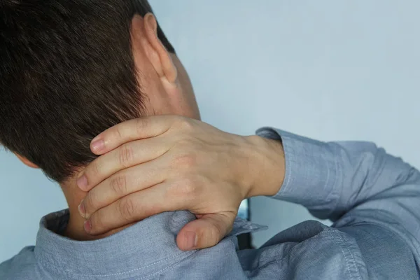 Der junge Mann hält sich den Hals. das Konzept der Gesundheit, Schmerzen im Nacken. Der Patient klagt über Halsschmerzen. Instabilität der Wirbel. Müdigkeit bei der Arbeit. — Stockfoto