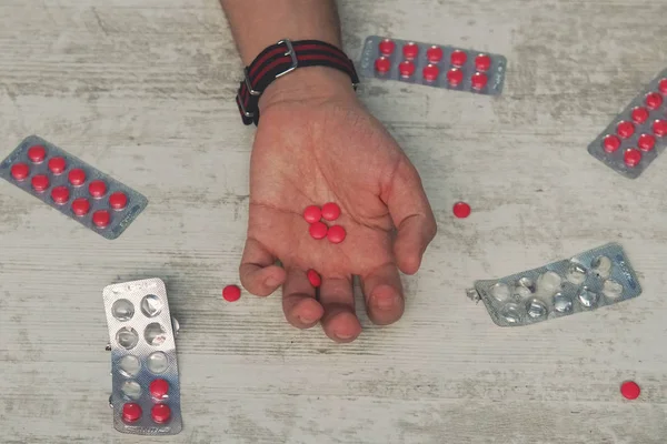 Samobójstwo, depresja i koncepcja przedawkowania martwy człowiek z butelką alkoholu i pigułki leżącego na stole w nocy, czerwone tabletki w ręku młodego mężczyzny — Zdjęcie stockowe