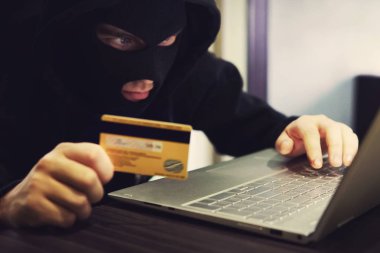 Soyguncu maskeli ve kapüşonlu adam kişisel banka verilerini kötüye kullandığını söyledi. Siber dolandırıcı online bankacılık sistemine saldırıyor. Hacker internet üzerinden mali dolandırıcılık yapar. Ödeme kartı kullanımı ile dijital suç.