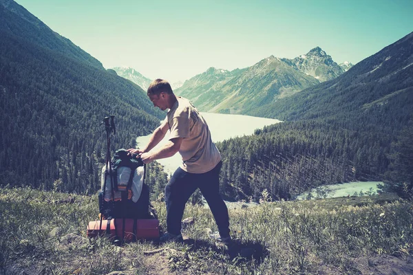 Man reiziger met rugzak bergbeklimmen reizen lifestyle concept. Backpacker met een grote rugzak kijkt naar de bergvallei met een prachtig groen meer. De natuur bewonderen — Stockfoto