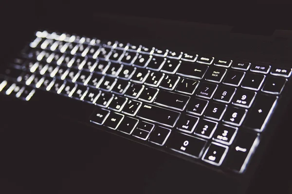 Brillant dans le clavier sombre. Lumière blanche sur clavier d'ordinateur portable . — Photo