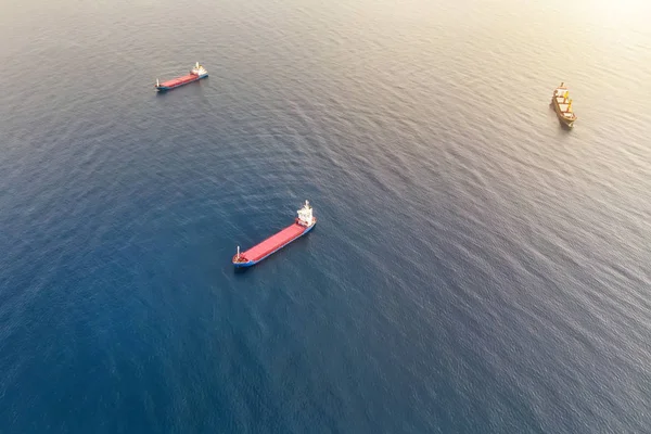 Vista aérea de tres buques portacontenedores en el mar dedicados al transporte de carga por agua. Carga de envío al puerto. Transporte por agua. Entrega náutica de contenedores. Buques de agua disparados arriba — Foto de Stock