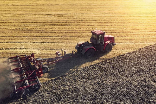Landbouwmachine oogsten gewas in velden. Tractor trekt een mechanisme voor hooi maken. Oogsten in de herfst in de ochtend bij zonsopgang. agribusiness in de regio Altai Rusland — Stockfoto