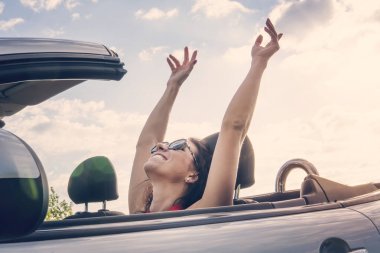 Mutlu kız yaz yol gezisi tatil seyahat sürüş üstü açılabilir arabada oturan güneşin tadını rahatlatıcı. Özgürlük kavramı kadın özgür duygu ellerini üst kaldırdı. rüzgar ile sürme.