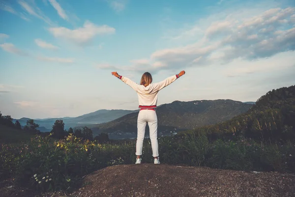 Gelukkig vieren winnende succes vrouw in witte kleren staan opgetogen met de armen opgeheven boven het hoofd ter viering van het hebben bereikt bergtop doel tijdens wandeltocht. — Stockfoto