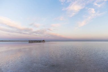 Güzel bir günbatımının arka planında, suyun yüzeyinde mayınlı tuz gezintileri yapan bir tren. Salt Lake Bursol, Burlinskoye Köyü. Altai bölgesi. Rusya.