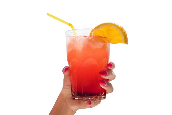 白い背景にオレンジが孤立したガラスの中で、手のひらに赤い飲み物を手に女性の手を閉じます。適切な栄養、ベジタリアンドリンク、健康的なライフスタイルの食事のコンセプト. — ストック写真