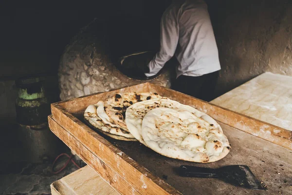 Ζεστό ψωμί. Κουζίνα της Κεντρικής Ασίας. ηλικιωμένος άνθρωπος κάνει παραδοσιακό ψωμί σε παλιό στρογγυλό πέτρινο φούρνο στο αγροτικό χωριό. — Φωτογραφία Αρχείου