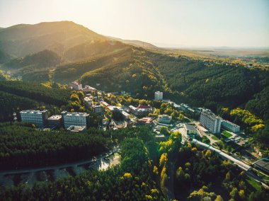 Belokurikha tatil köyünün en iyi manzarası. Dağların yamaçlarındaki ormanların arasındaki evlerin kuş bakışı görüntüsü. Altai bölgesindeki küçük bir kasabanın havadan görünüşü
