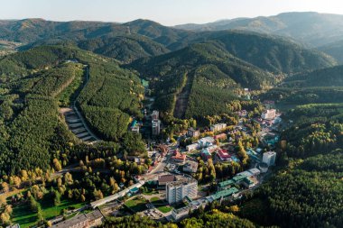 Belokurikha tatil köyünün en iyi manzarası. Dağların yamaçlarındaki ormanların arasındaki evlerin kuş bakışı görüntüsü. Altai bölgesindeki küçük bir kasabanın havadan görünüşü