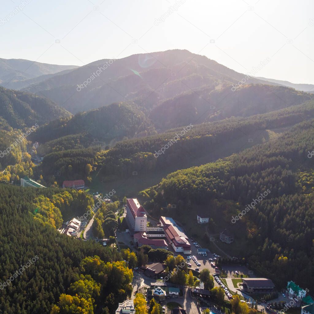 Top view of the resort town Belokurikha. Bird's-eye view of the houses among the forests on the slopes of the mountains. Aerial view of a small town in the Altai territory