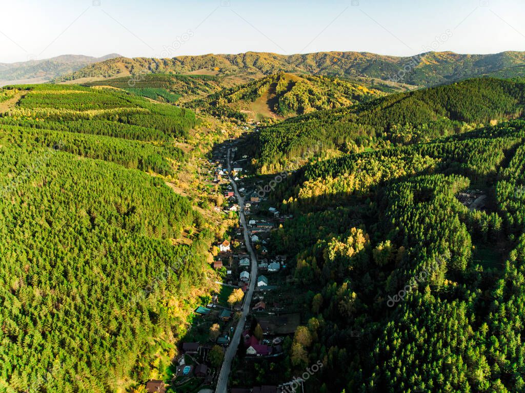 Top view of the resort town Belokurikha. Bird's-eye view of the houses among the forests on the slopes of the mountains. Aerial view of a small town in the Altai territory