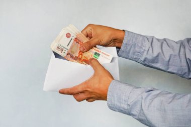 Süpermarket raflarına karşı zarfında ruble olan bir el. Erkek eller rubleyi 5.000 ruble olarak kabul eder.
