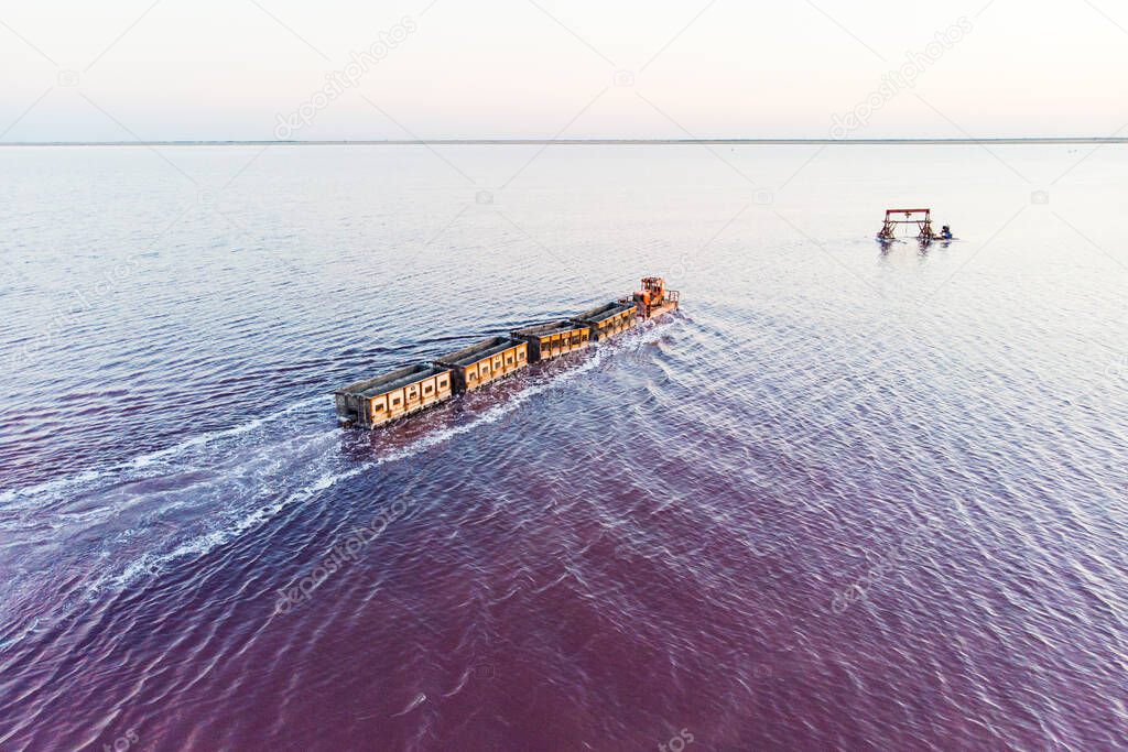 Old train rides on the railway laid in the water through the salt lake. train travels from water. Mined salt in Lake Burlin. Altai. Russia. Bursolith. aerial view, view from the top