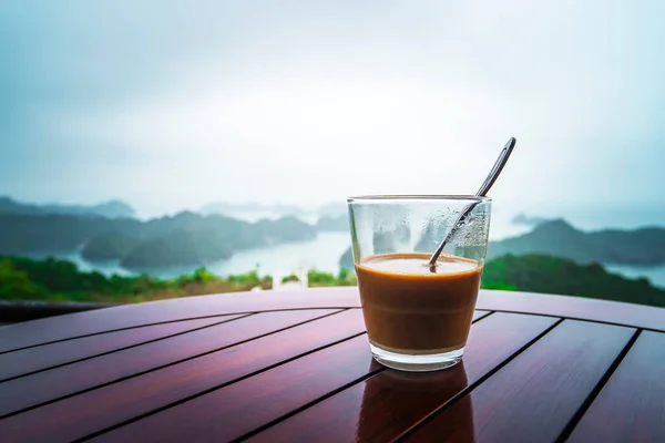 Hot milk coffee in Vietnam style. Breakfast with a beautiful view against the rocks sticking out of the water into the sea. Ha long Bay in Northern Vietnam. copy space