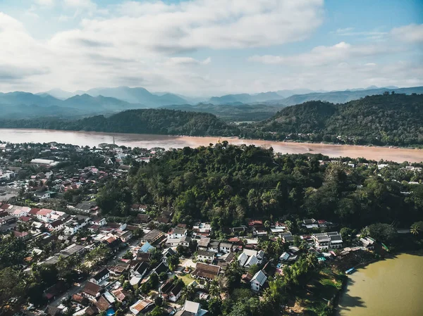 Luang Prabang, Laos. Luchtfoto van Luang Prabang stad in Laos. Wolken lucht boven kleine stad omgeven door bergen. Autoverkeer en rivier — Stockfoto