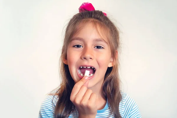 cleaning your teeth with chewing gum. girl puts white gum shaped pads in her open mouth. bad habit, harmful habit, pernicious habit, unhealthy habit