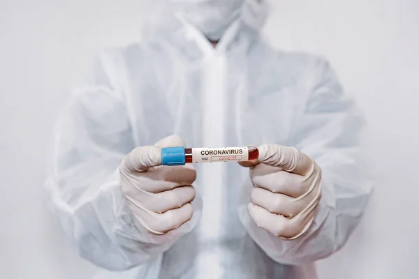 Коронавірус коїд 19 заражений зразком крові в пробірці в руці вченого з біогазовим захисним одягом в дослідницькій лабораторії коронавірусу. Доктор рука тримає пробірку з кров'ю — стокове фото