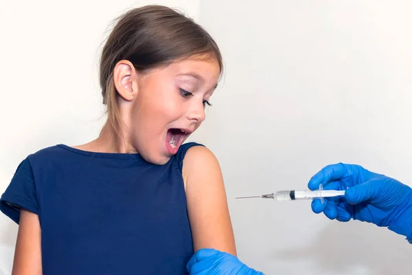 A little girl screams in fear of being shot in the shoulder. Vaccination against dangerous viral diseases. Prevention and protection from viruses. Injection of antibodies. Medical concept.