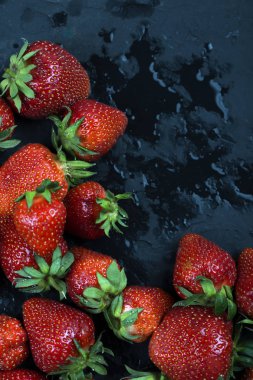 Bütün çilek su siyah zemin üzerine bırakır. Islak çilek. Çerçeve, kopya alanı.