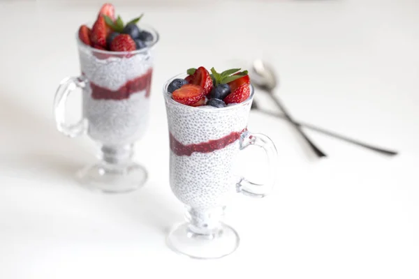Portion of chia pudding with vegan almond milk, blueberry & strawberry, mint, served in glass. Healthy vegetarian breakfast, seeds berries, greek yogurt. Background, close up, copy space